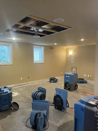Dehumidifiers and air movers drying a finished basement with an opened ceiling in Overland Park