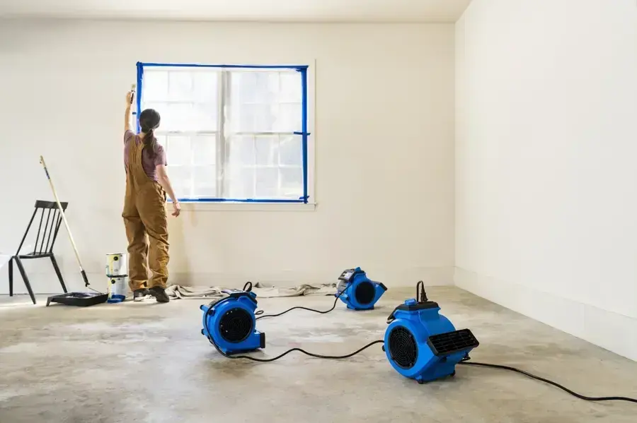 Restoration tech setting up air movers to dry a room after water damage in Overland Park