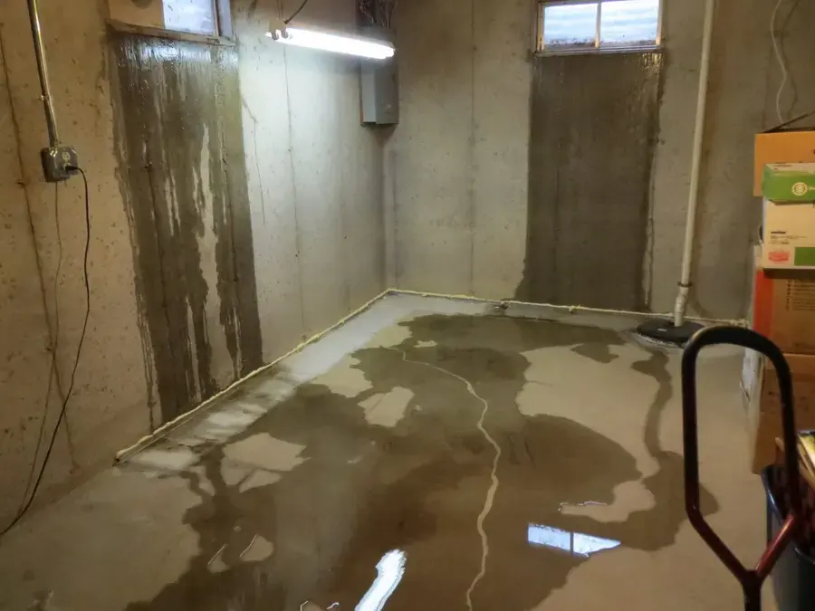 Water seeping across a basement floor from a foundation wall in Overland Park